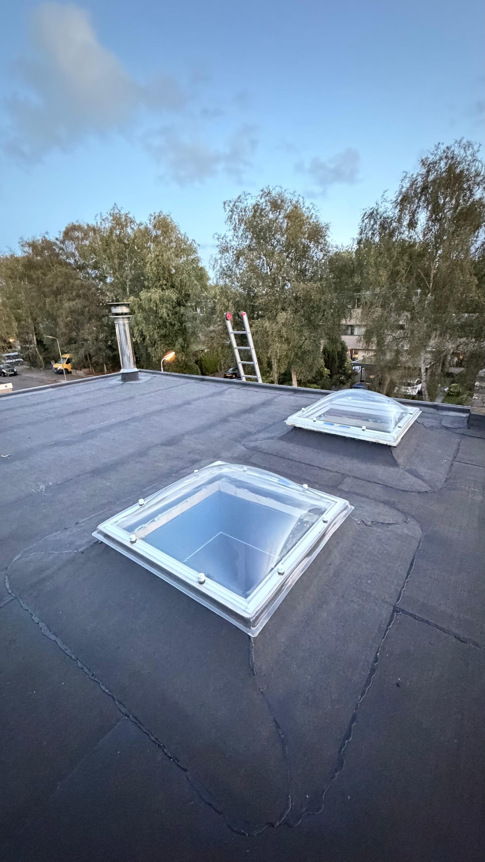 Opgeleverd plat dak met nieuwe bitumen dakbedekking en twee lichtkoepels